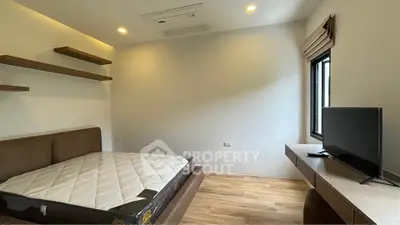 Modern minimalist bedroom with wooden flooring and mounted TV