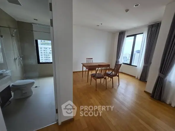 Spacious apartment with wooden flooring and large windows offering city views.