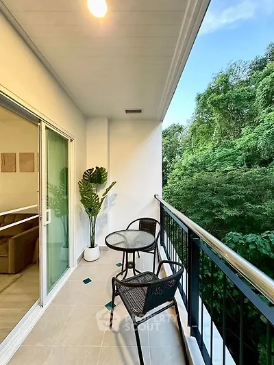 Charming balcony with lush green view and cozy seating area, perfect for relaxation.
