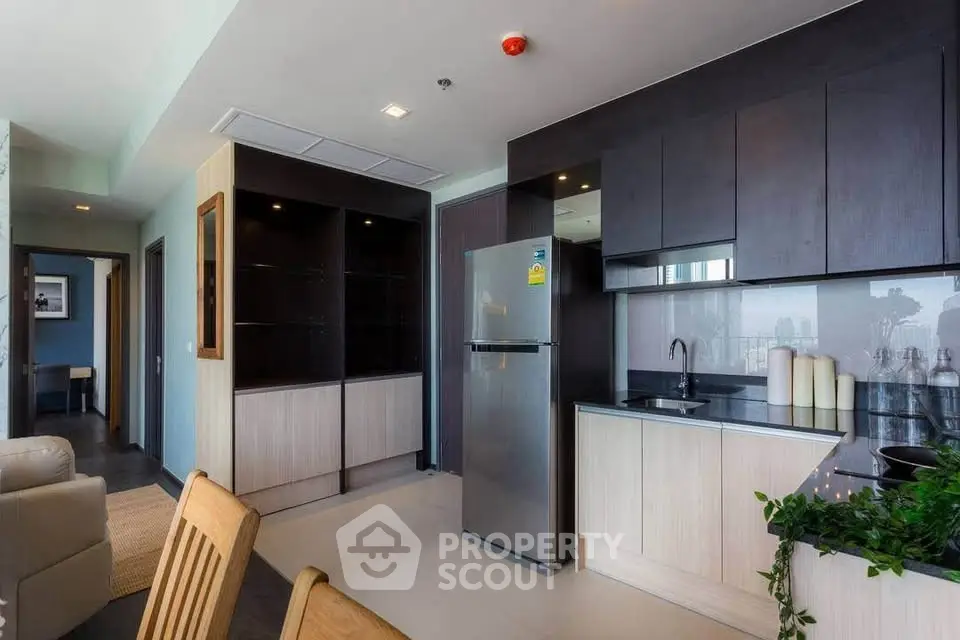 Modern kitchen with sleek cabinets and stainless steel fridge in open layout apartment.