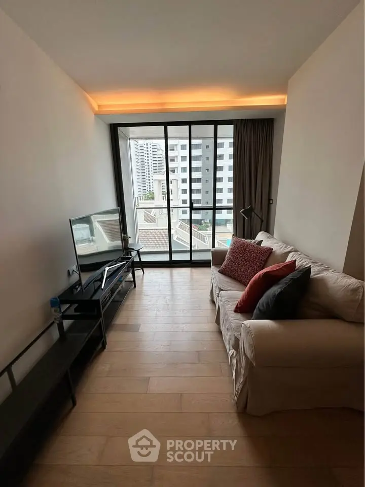 Modern living room with city view, featuring cozy sofa and large windows for natural light.