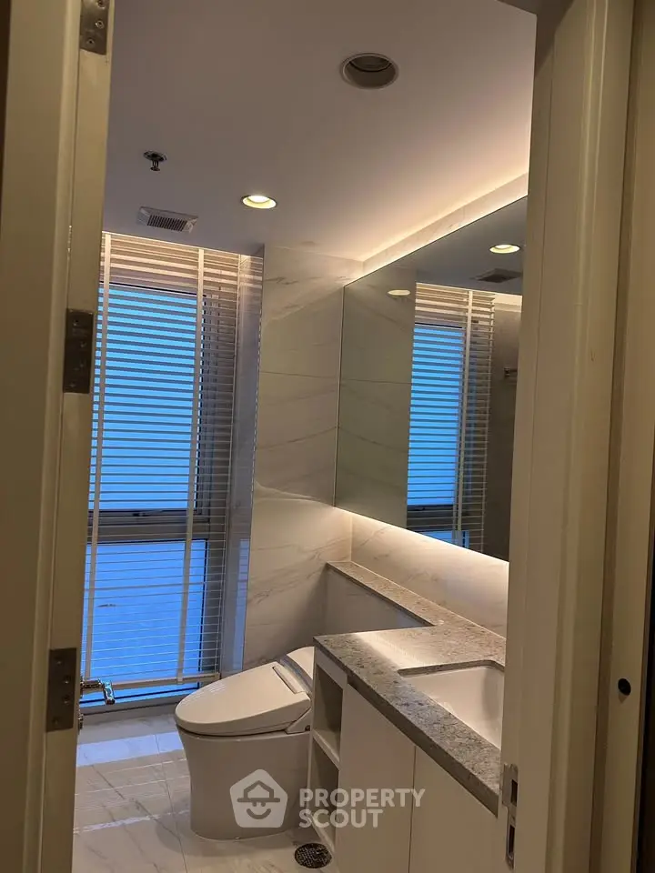 Modern bathroom with sleek design, featuring marble countertops and large mirror.