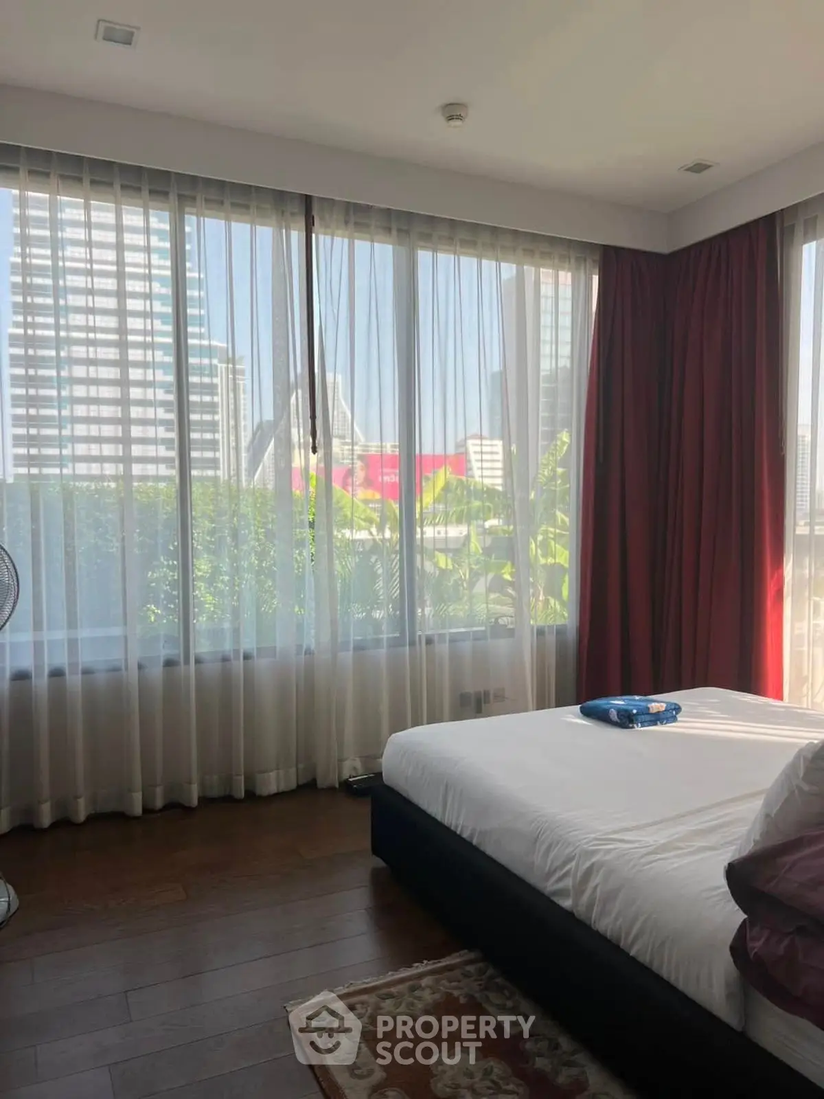 Spacious bedroom with large windows offering a stunning city view, perfect for urban living.