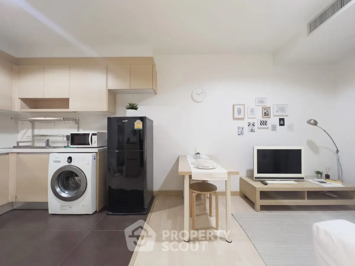 Modern studio apartment with open kitchen, washing machine, and cozy living area.