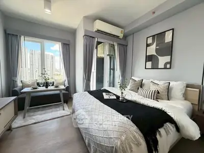 Modern bedroom with city view, stylish decor, and cozy seating area.