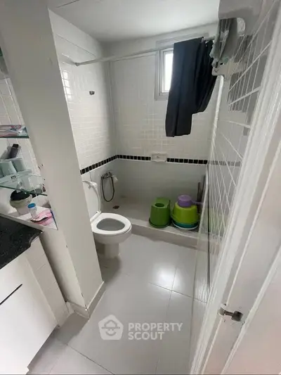 Compact bathroom with modern fixtures and tiled walls, featuring a small window for natural light.