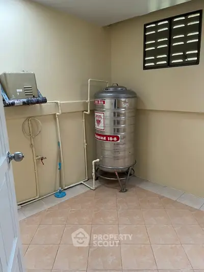 Utility room with water tank and tiled floor in a residential property.