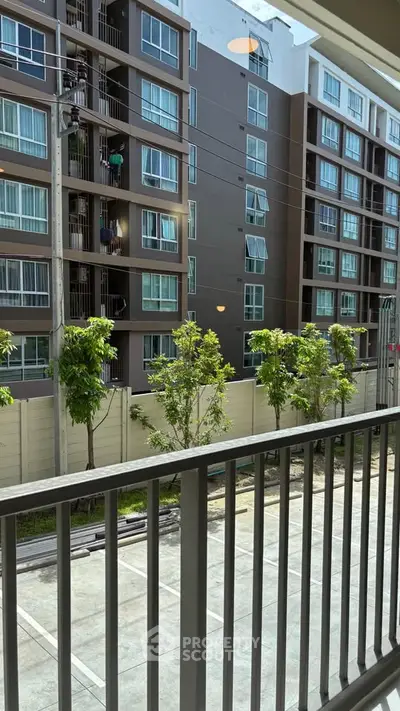 Modern apartment building view from balcony with lush greenery and urban surroundings.