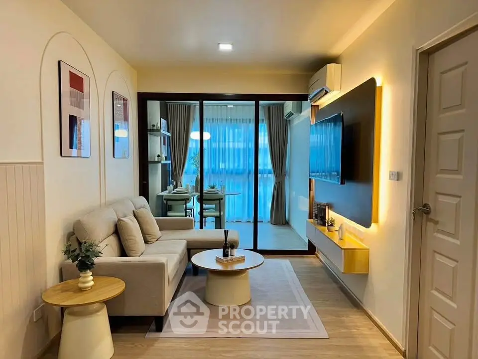 Modern living room with cozy sofa and stylish decor, leading to a bright dining area with large windows.