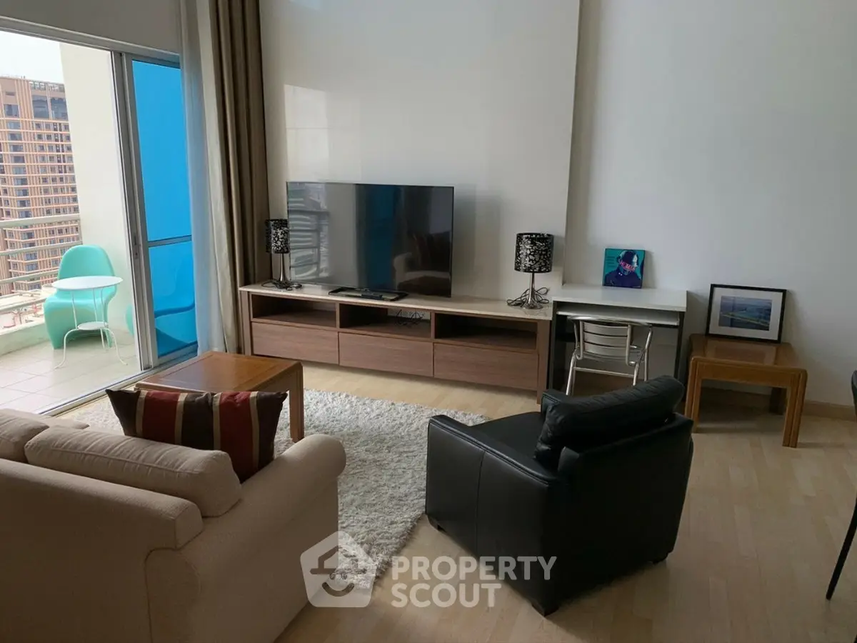 Modern living room with balcony access and stylish furniture in a high-rise apartment.