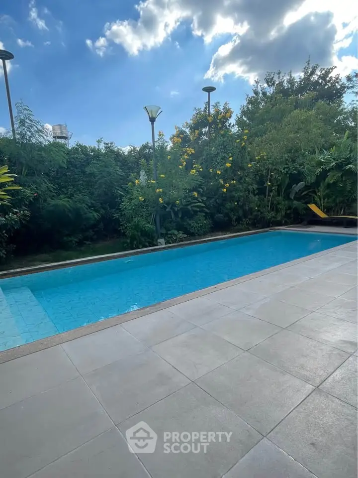 Luxurious outdoor pool with lush greenery and clear blue sky