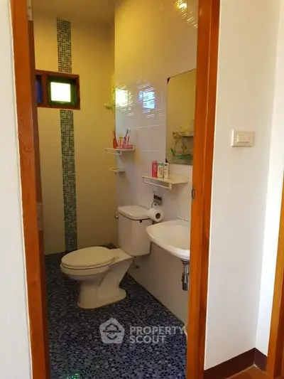 Compact bathroom with modern fixtures and vibrant blue tile flooring.
