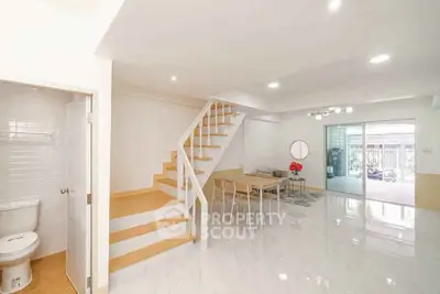 Modern open-plan living room with staircase and dining area, bright and spacious design.