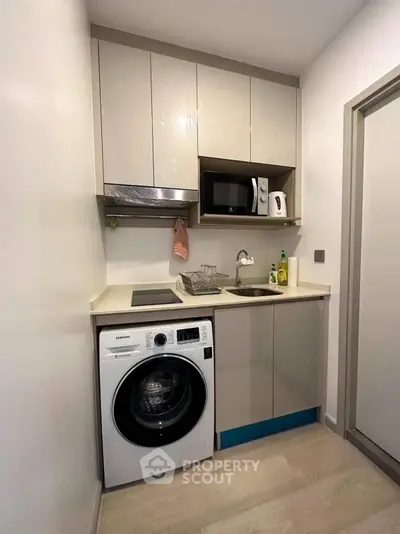 Compact modern kitchen with washing machine and microwave in sleek apartment