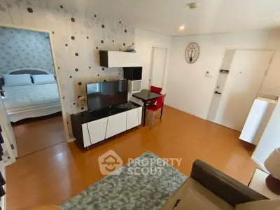 Modern living room with stylish decor and adjacent bedroom, featuring hardwood floors and contemporary furniture.