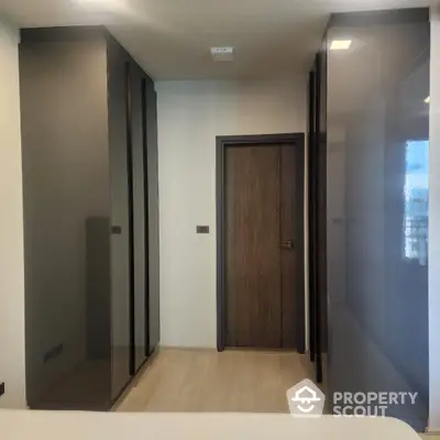 Modern bedroom with sleek dark wardrobes and wooden door