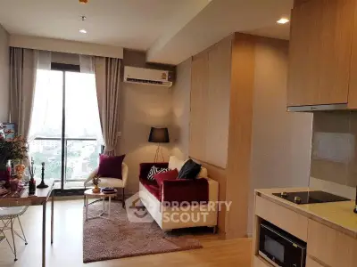 Modern living room with open kitchen, featuring cozy seating and large window with city view.