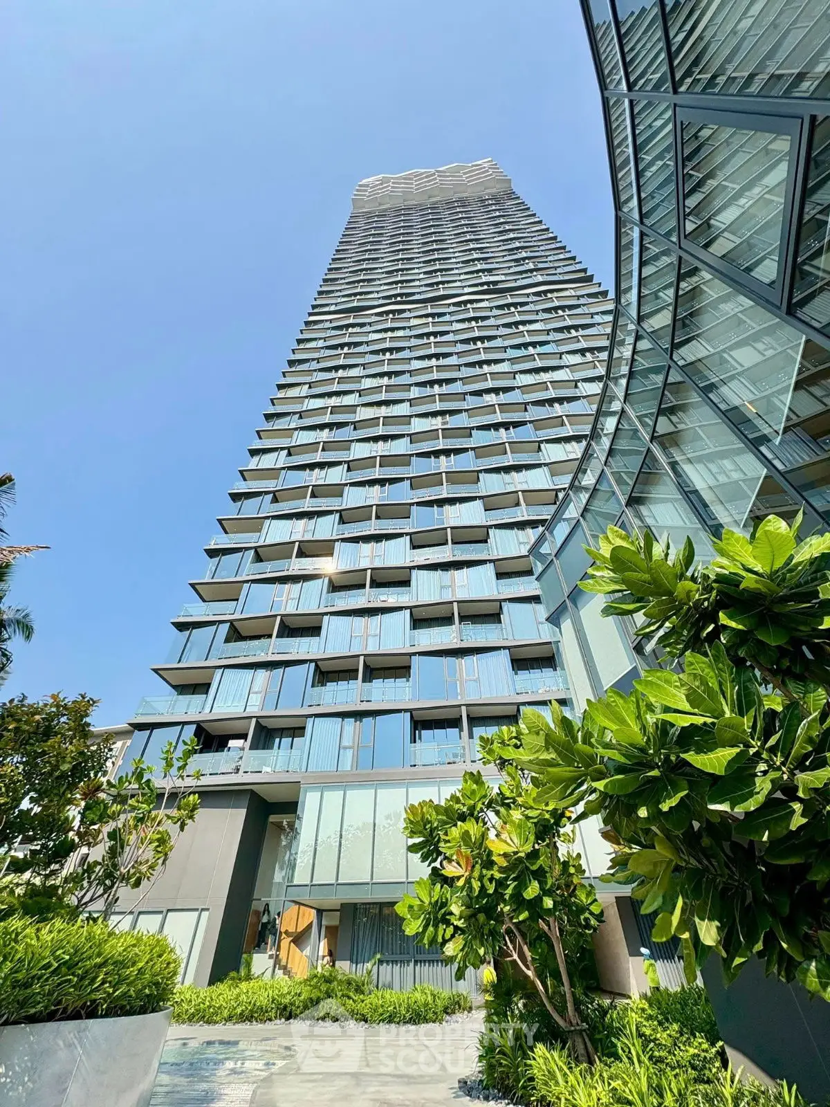 Stunning modern high-rise building with lush greenery and sleek architectural design.