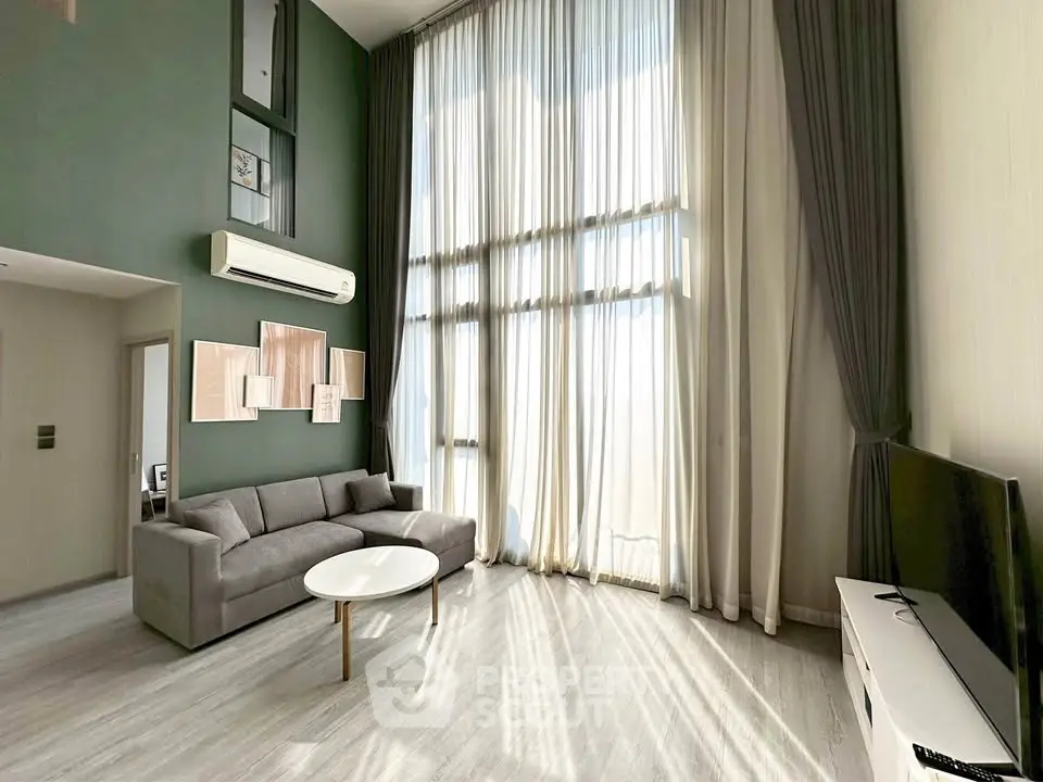 Spacious modern living room with high ceilings and large windows, featuring elegant curtains and a cozy sofa.