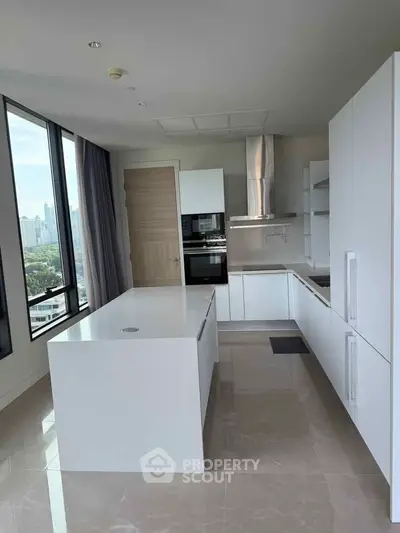 Modern kitchen with sleek white cabinetry and island, featuring city views through large windows.
