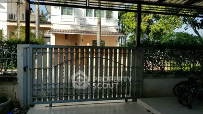 Spacious gated entrance with tiled flooring and lush greenery, perfect for secure and serene living.