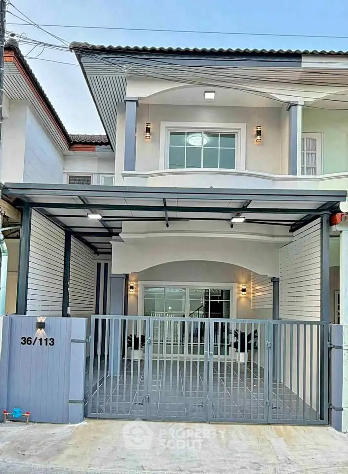 Modern two-story house with gated entrance and sleek exterior design.