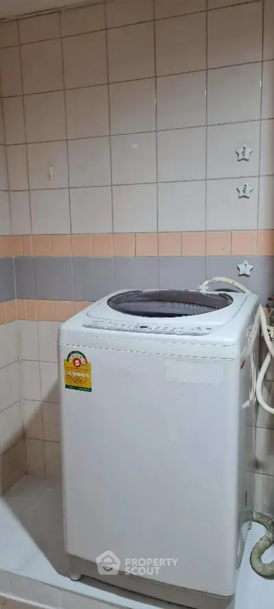 Compact laundry area with washing machine in tiled room, ideal for efficient home living.