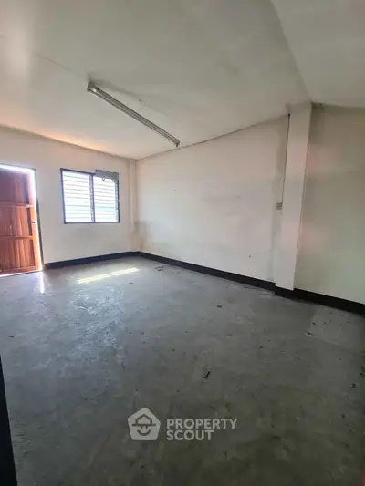 Spacious empty room with natural light and concrete flooring, ideal for customization.
