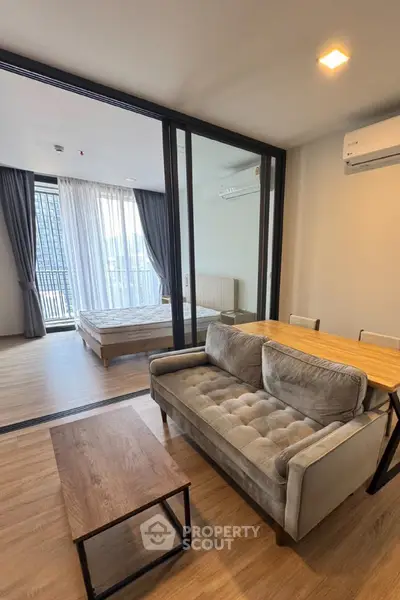 Modern apartment with open living room and bedroom, featuring stylish furniture and large windows.
