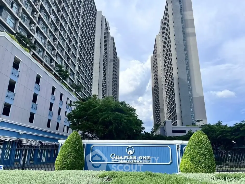 Modern high-rise residential complex with lush greenery and elegant entrance sign.