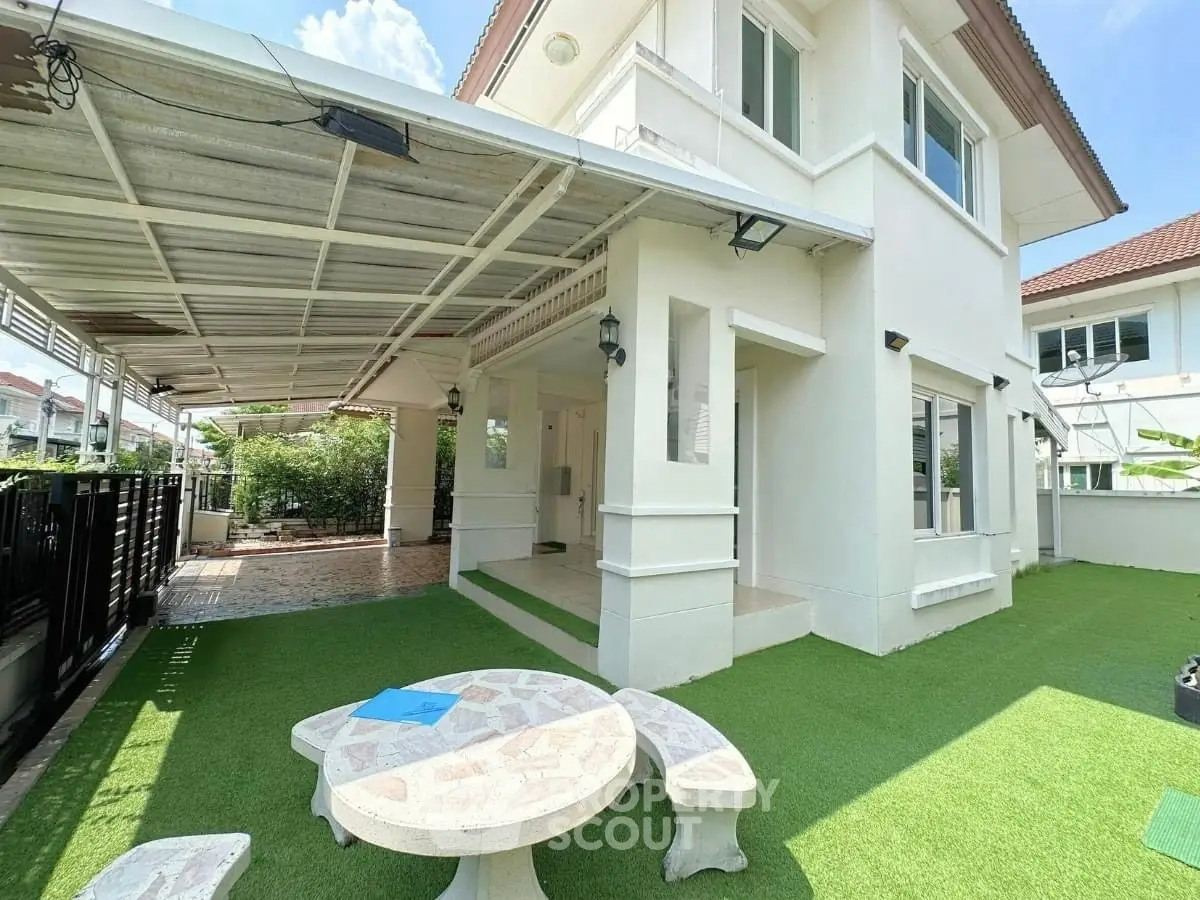 Charming two-story home with spacious covered patio and lush artificial grass yard, perfect for outdoor relaxation.