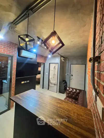 Industrial-style interior with exposed brick, modern lighting, and sleek finishes in a compact living space.