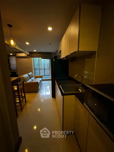 Modern kitchen with sleek cabinetry and open layout leading to cozy living area.