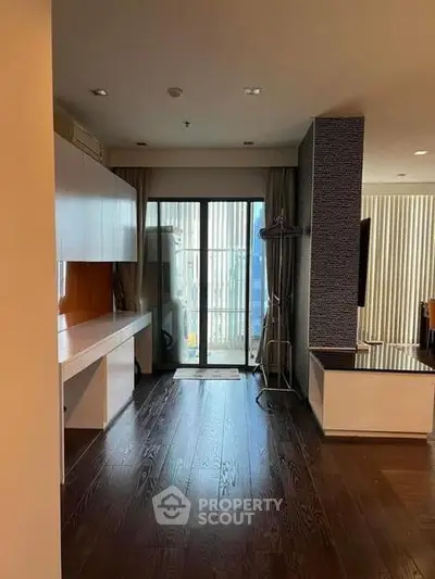 Spacious modern living area with dark wood flooring and balcony access