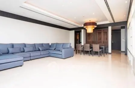 Spacious living room with modern sectional sofa and elegant dining area in luxury apartment.