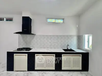 Modern kitchen with sleek black and white design, featuring gas stove and stylish cabinetry.