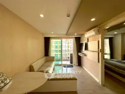 Modern living room with open layout and balcony access, featuring sleek furniture and ample natural light.