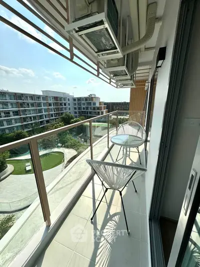 Modern balcony with stylish chairs and scenic view of residential complex and greenery.