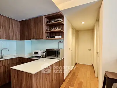 Modern kitchen with sleek wooden cabinets and built-in appliances in a cozy apartment setting.