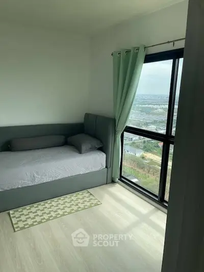 Cozy bedroom with large window offering stunning city view, featuring modern decor and natural light.