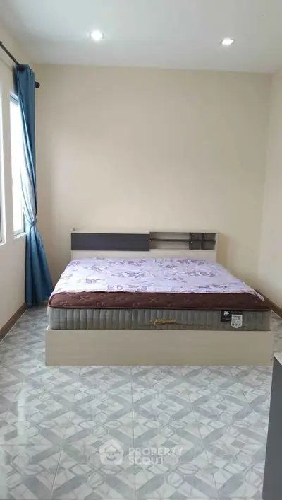 Spacious bedroom with modern bed and natural light from large windows.