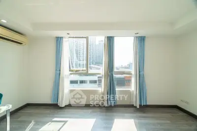 Bright modern room with large windows and city view, featuring sleek flooring and air conditioning.