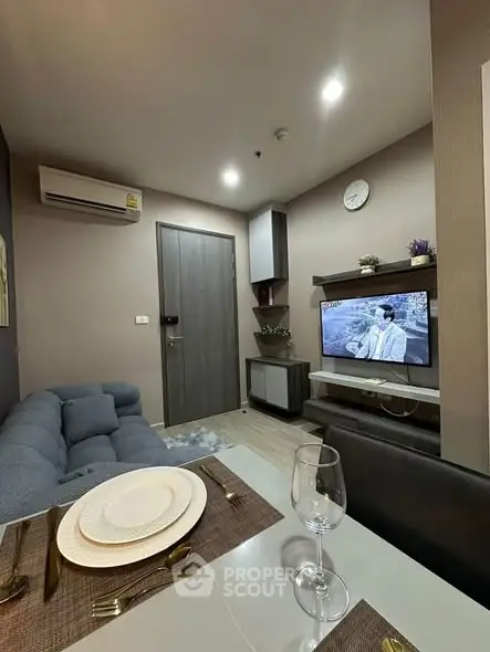 Modern living room with cozy sofa, dining area, and wall-mounted TV in stylish apartment.