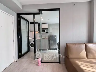 Modern apartment interior with glass partition, featuring a compact kitchen and cozy living area.