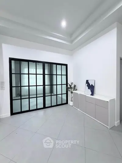 Modern minimalist interior with sleek sliding glass doors and stylish storage unit, perfect for contemporary living.