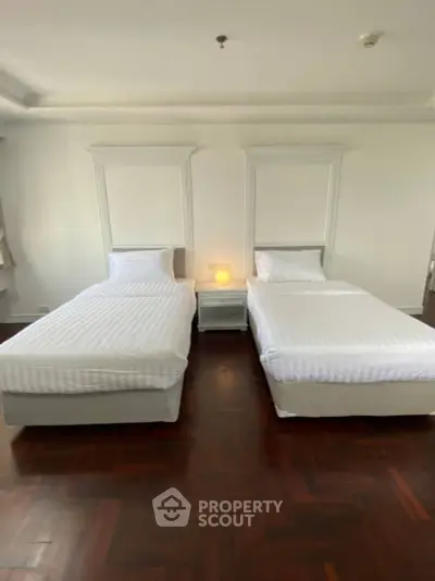 Spacious bedroom with twin beds and elegant wooden flooring