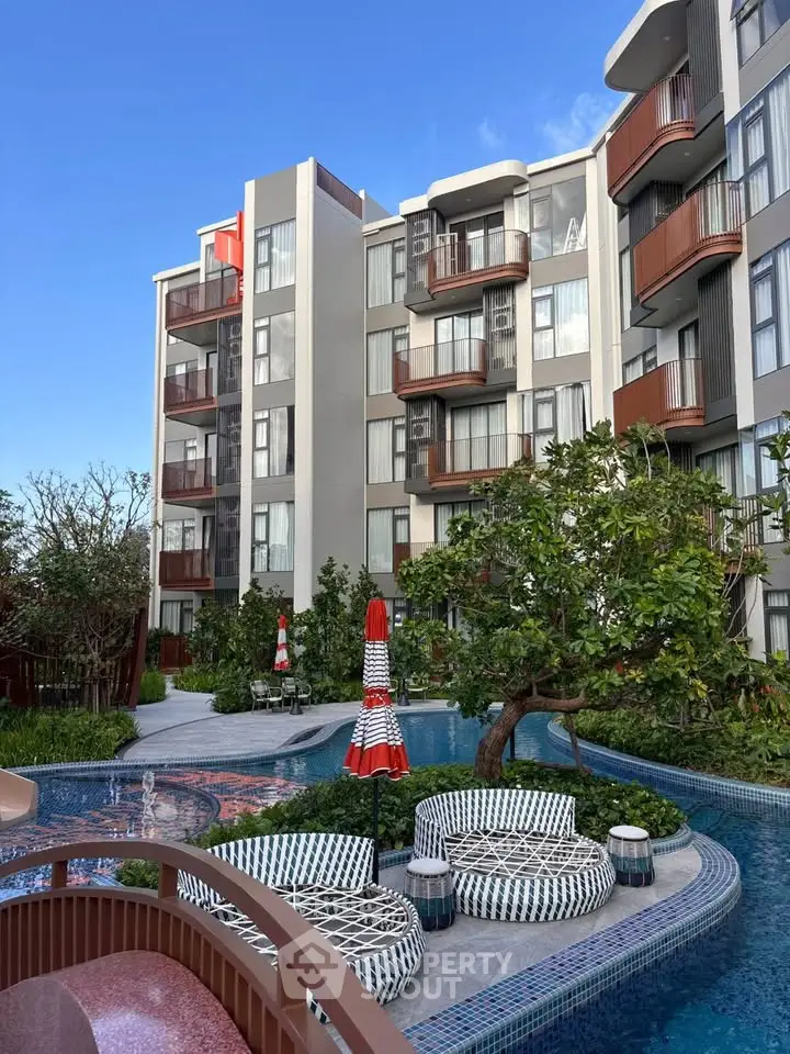 Modern apartment building with stylish pool and lush garden area.