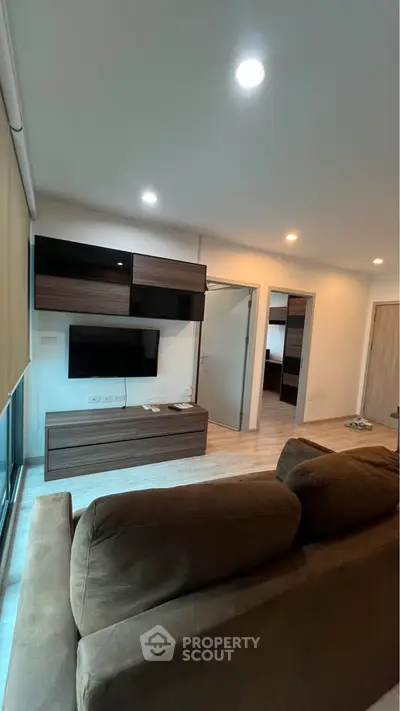 Modern living room with sleek furniture and wall-mounted TV in a cozy apartment.