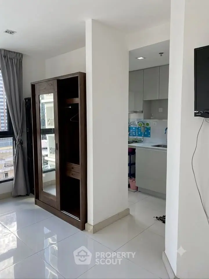 Modern apartment interior with sleek kitchen and stylish wardrobe, featuring large windows for natural light.