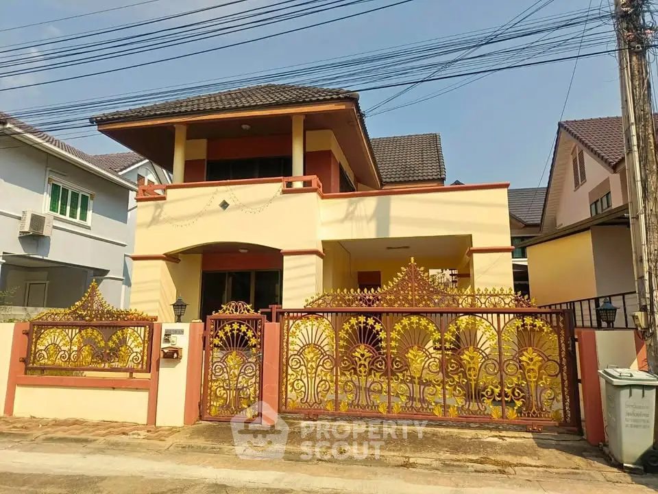 Charming two-story house with ornate yellow gate and tiled roof in suburban neighborhood.